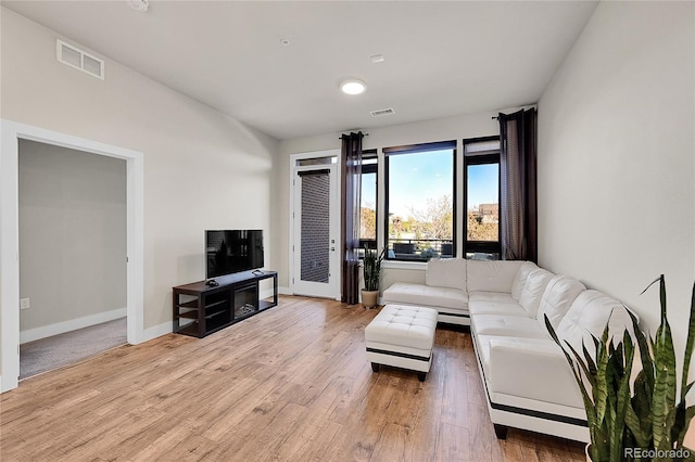 living area with visible vents, baseboards, and light wood-type flooring