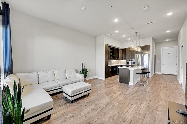 living area featuring recessed lighting, baseboards, visible vents, and light wood-style flooring