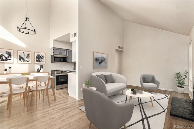 living room featuring high vaulted ceiling and light hardwood / wood-style flooring