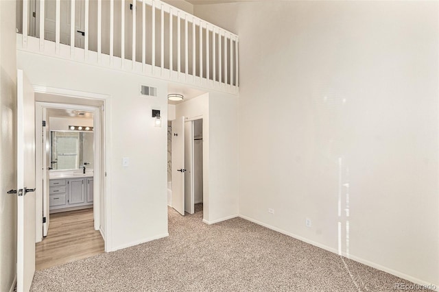 spare room featuring a towering ceiling and light colored carpet