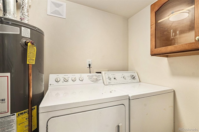 laundry room with cabinets, water heater, and washing machine and clothes dryer