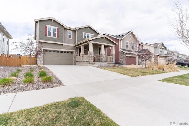 craftsman-style house featuring a garage, stone siding, driveway, and fence