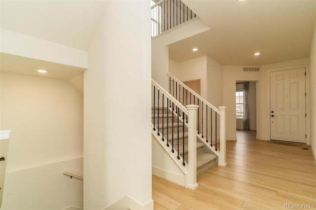 stairs featuring baseboards, visible vents, wood finished floors, and recessed lighting