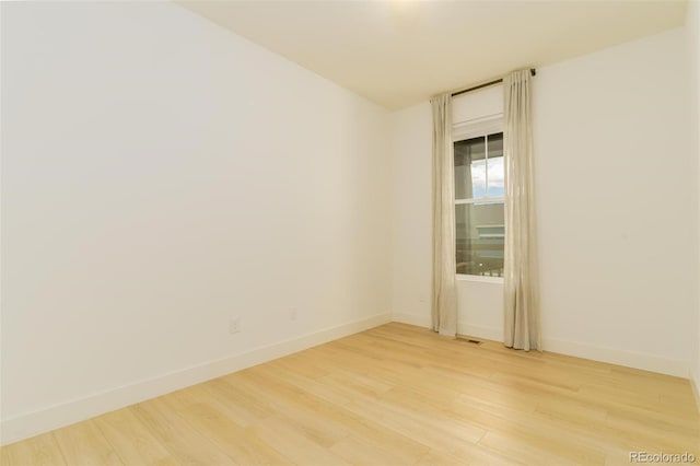 spare room featuring visible vents, light wood-style flooring, and baseboards