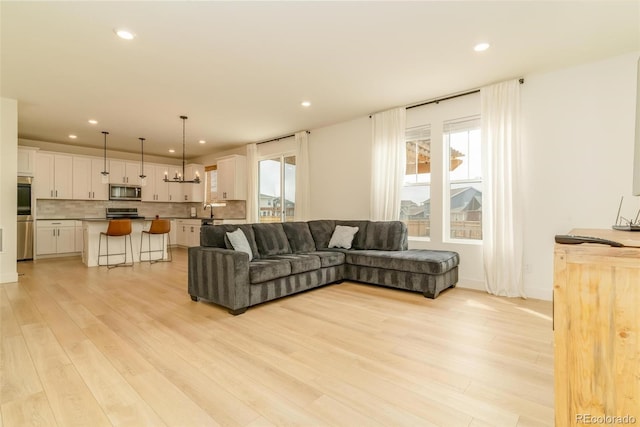 living room with plenty of natural light, a chandelier, light wood-style flooring, and recessed lighting