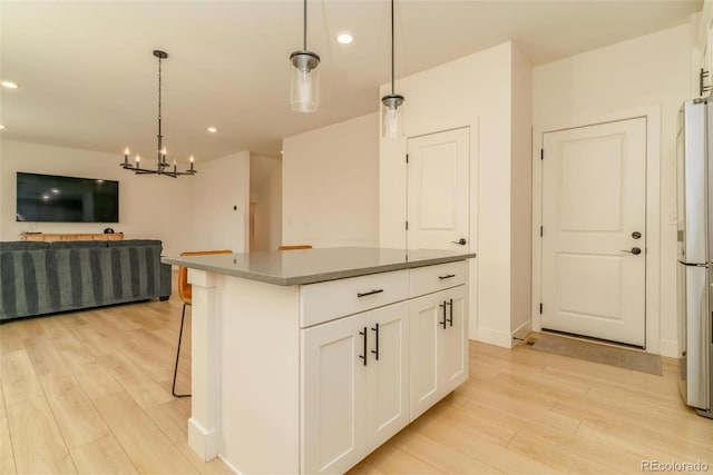 kitchen with light wood-type flooring, open floor plan, white cabinetry, and hanging light fixtures