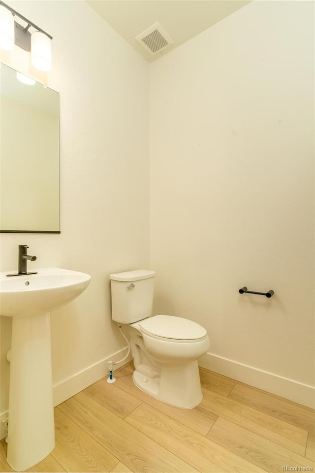 bathroom featuring toilet, wood finished floors, visible vents, and baseboards