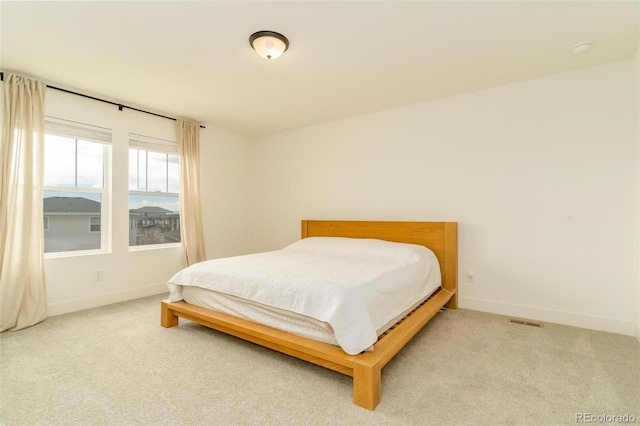 bedroom with light carpet, visible vents, and baseboards