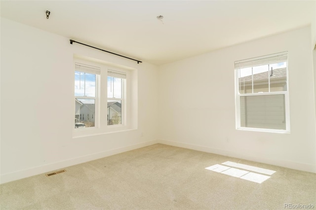 unfurnished room featuring carpet flooring, visible vents, and baseboards