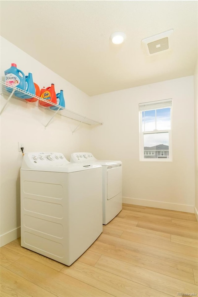 laundry area featuring light wood-type flooring, laundry area, baseboards, and separate washer and dryer