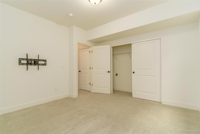 unfurnished bedroom with light carpet, a closet, and baseboards