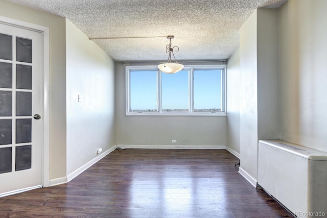 spare room featuring dark hardwood / wood-style floors and a textured ceiling