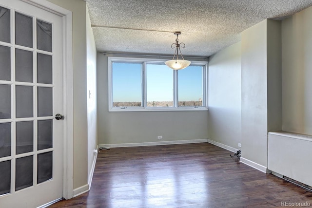 empty room with dark hardwood / wood-style flooring, radiator, and a textured ceiling