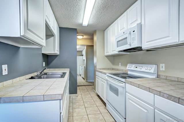 kitchen featuring sink, white appliances, tile countertops, and white cabinets