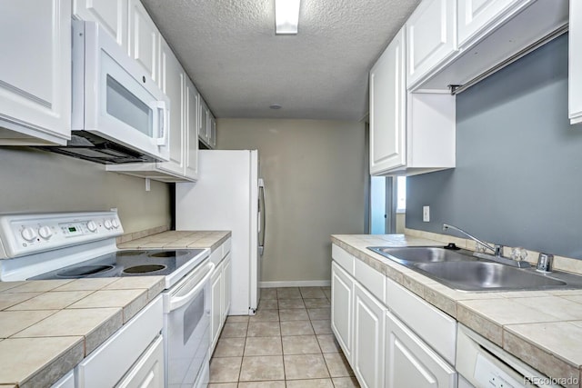 kitchen with white cabinetry, sink, tile counters, and white appliances