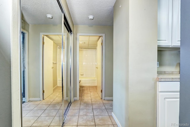 hallway with light tile patterned floors and a textured ceiling