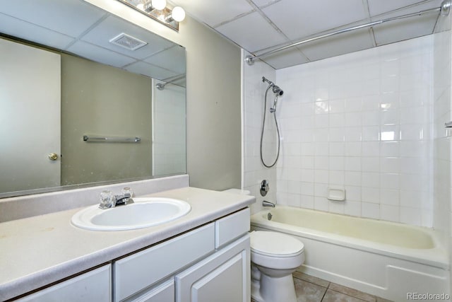 full bathroom featuring tiled shower / bath, a paneled ceiling, vanity, toilet, and tile patterned floors