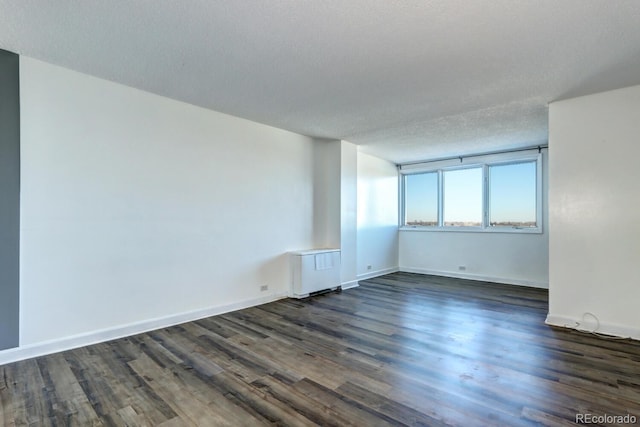 unfurnished room with radiator heating unit, dark hardwood / wood-style flooring, and a textured ceiling