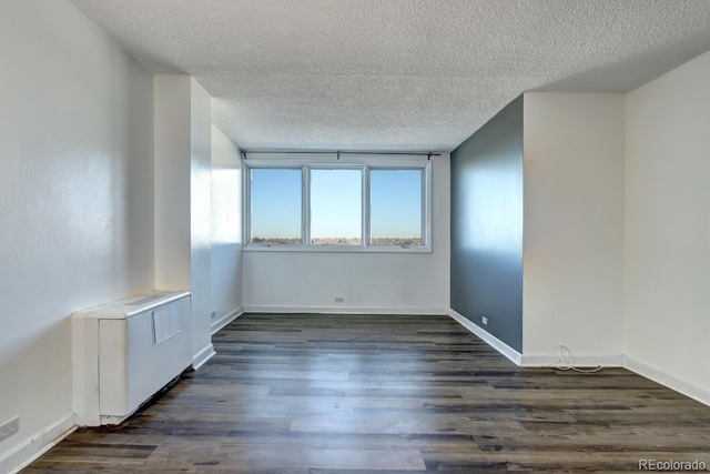 empty room with dark wood-type flooring and a textured ceiling