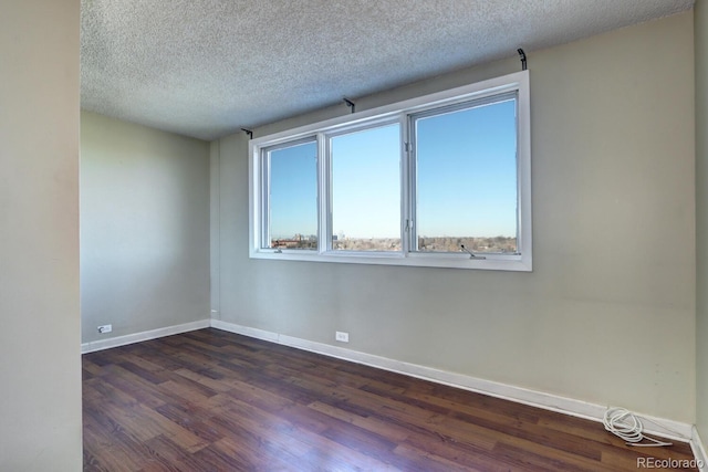 empty room featuring dark wood-type flooring and a textured ceiling