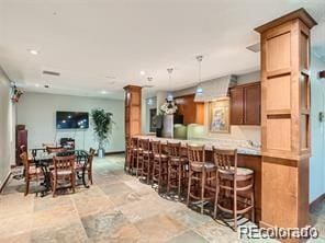 kitchen with decorative light fixtures, a kitchen breakfast bar, decorative columns, and kitchen peninsula