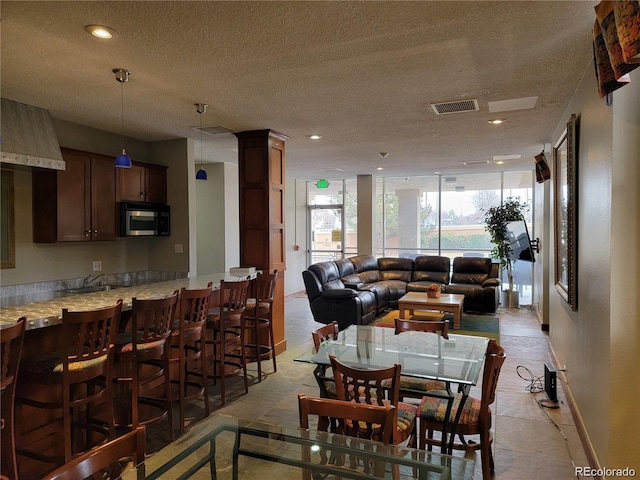 dining area featuring ornate columns, a textured ceiling, and light tile patterned flooring