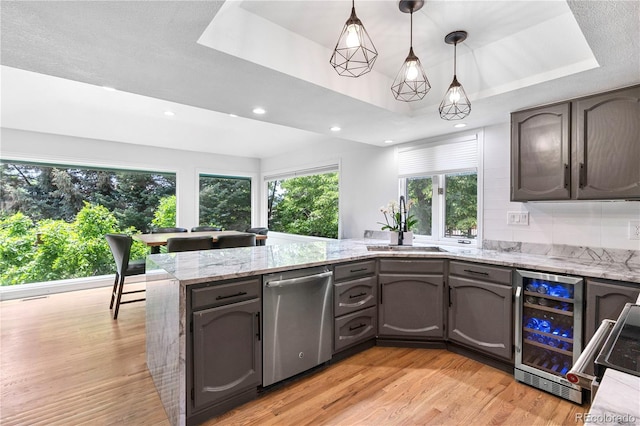 3253 S King Way, Denver, CO 80236 - kitchen featuring stainless steel dishwasher, beverage cooler, a peninsula, a raised ceiling, and light wood finished floors