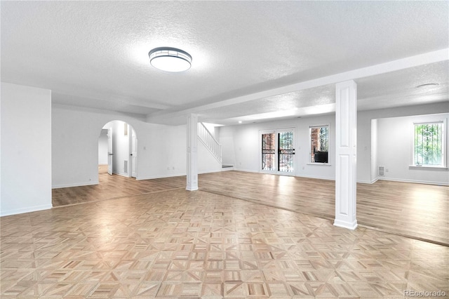 3253 S King Way, Denver, CO 80236 - basement featuring a textured ceiling, stairs, baseboards, and arched walkways