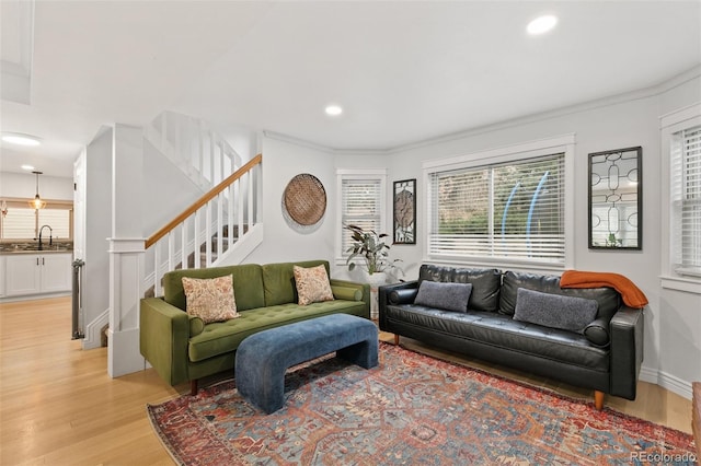 living room with light hardwood / wood-style floors, crown molding, and sink