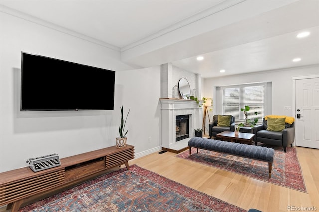 living room with a fireplace, light hardwood / wood-style floors, and ornamental molding