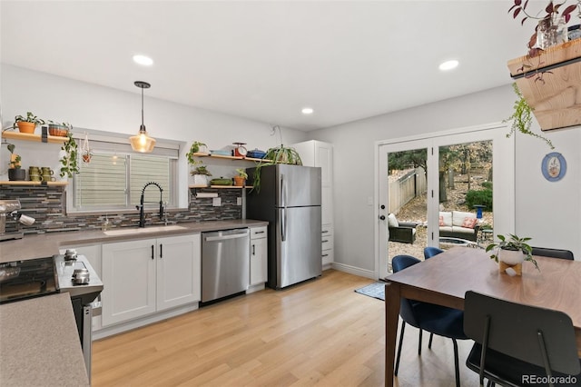 kitchen featuring appliances with stainless steel finishes, sink, decorative light fixtures, light hardwood / wood-style flooring, and white cabinets