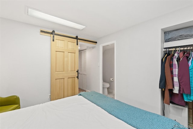 bedroom featuring connected bathroom, a barn door, and a closet