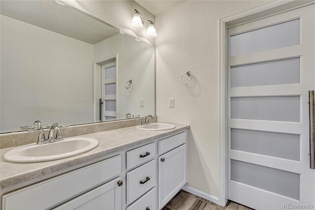 14902 E Poundstone Dr, Aurora, CO 80015 - full bathroom with double vanity, a textured wall, and wood finished floors