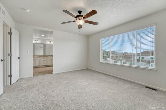 14902 E Poundstone Dr, Aurora, CO 80015 - unfurnished bedroom featuring multiple windows, light carpet, baseboards, ensuite bath, and a textured ceiling