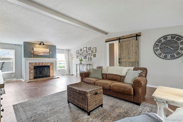 16580 Sagecreek Rd, Peyton, CO 80831 - living room with a barn door, wood finished floors, a brick fireplace, a textured ceiling, and baseboards