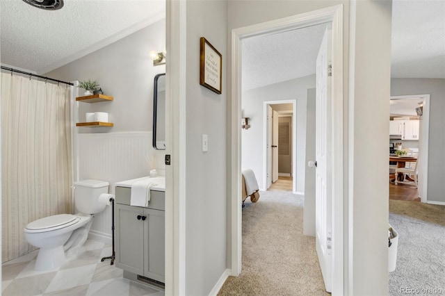 16580 Sagecreek Rd, Peyton, CO 80831 - bathroom featuring a textured ceiling, vanity, toilet, curtained shower, and a wainscoted wall