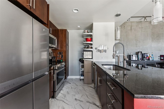 kitchen featuring appliances with stainless steel finishes, dark brown cabinets, dark stone counters, hanging light fixtures, and sink