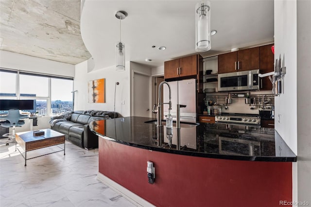 kitchen with decorative light fixtures, refrigerator, dark stone countertops, stove, and sink