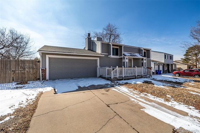 view of front of home featuring brick siding, an attached garage, a chimney, driveway, and fence