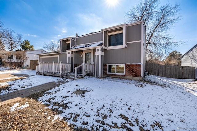 view of front of property featuring a garage, brick siding, and fence