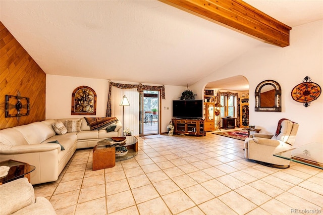 living room featuring light tile patterned floors, vaulted ceiling with beams, arched walkways, wood walls, and a textured ceiling