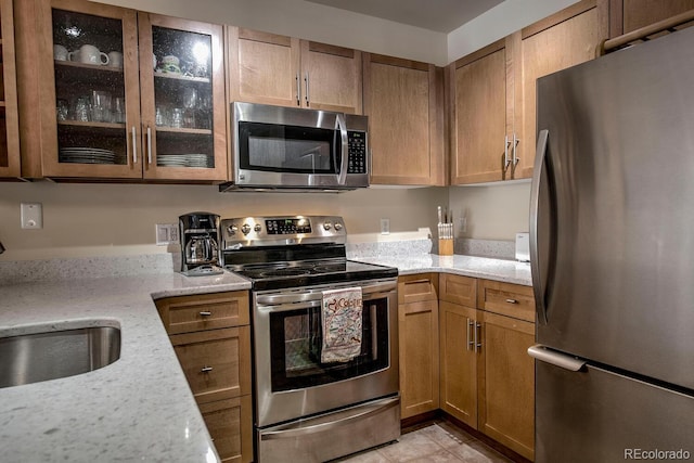 105 Wheeler Cir Unit 334, Frisco, CO 80443 - kitchen with stainless steel appliances, light stone countertops, glass insert cabinets, light tile patterned flooring, and brown cabinets