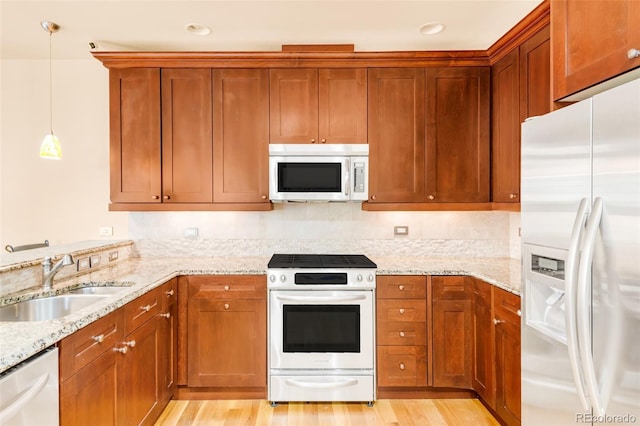 kitchen with dishwasher, range with gas stovetop, sink, light stone counters, and fridge with ice dispenser