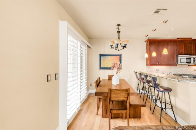 dining area with light hardwood / wood-style flooring and an inviting chandelier