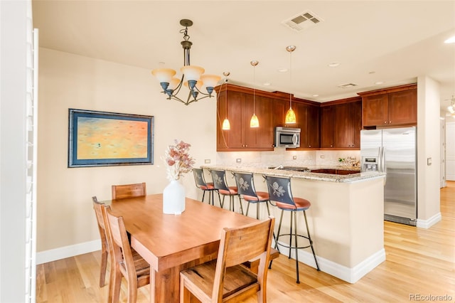 dining room with light wood-type flooring and a notable chandelier