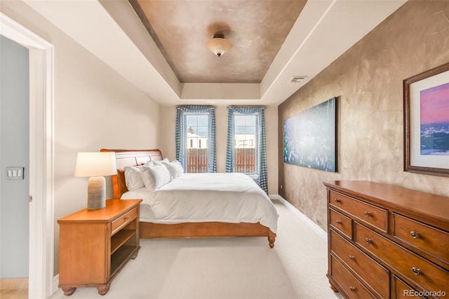 carpeted bedroom with a raised ceiling