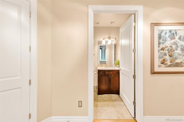 hallway featuring sink and light tile patterned flooring