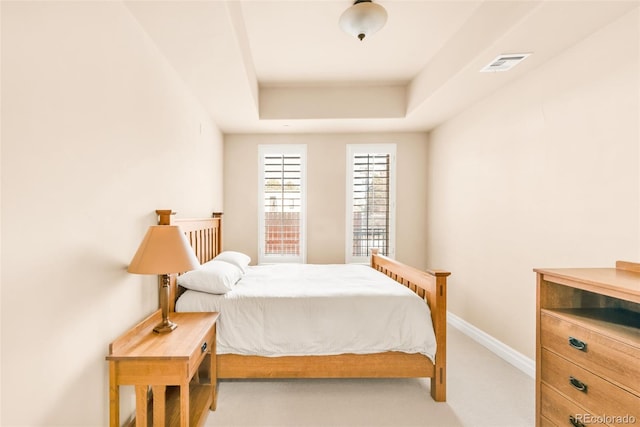 bedroom with carpet floors and a raised ceiling