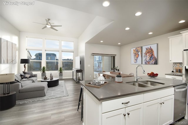 kitchen featuring a center island with sink, sink, stainless steel dishwasher, light hardwood / wood-style floors, and white cabinetry