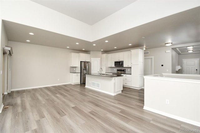 kitchen featuring a kitchen island with sink, white cabinets, sink, tasteful backsplash, and stainless steel appliances